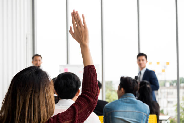 istock A woman is raising hand up while businessman is speaking in training at the office. 1053768596