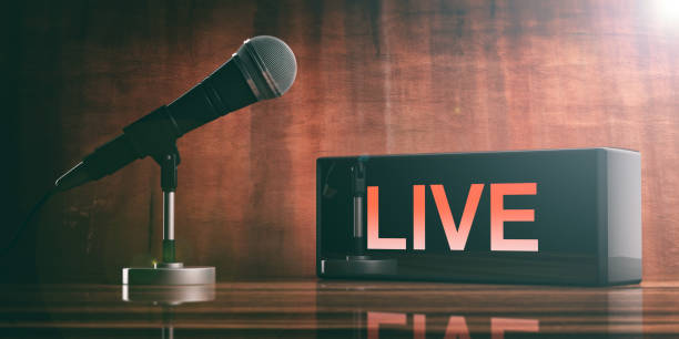 istock LIVE on a black box and a microphone on a wooden desk. 3d illustration 1053768990