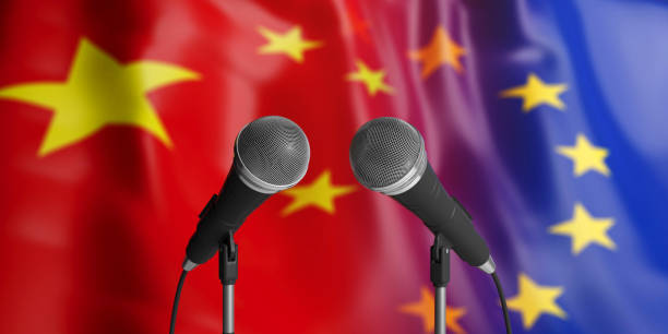 istock EU and China relations. Two cable microphones in front. Flags for background. 3d illustration 1053769020