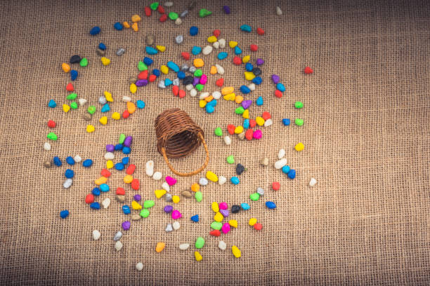istock Basket and spilled colorful pebbles  on canvas background 1053770506