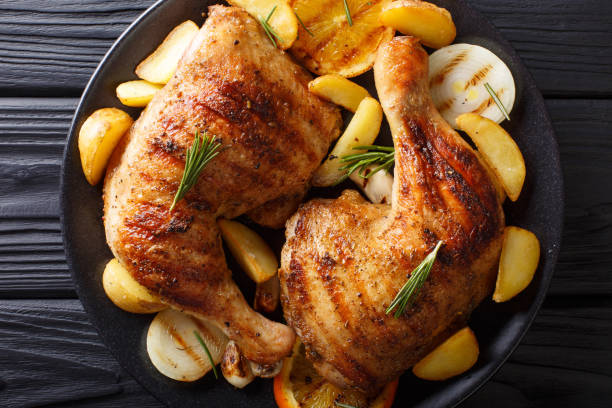 istock grilled chicken leg with oranges, onions and potatoes macro. Horizontal top view 1053772570
