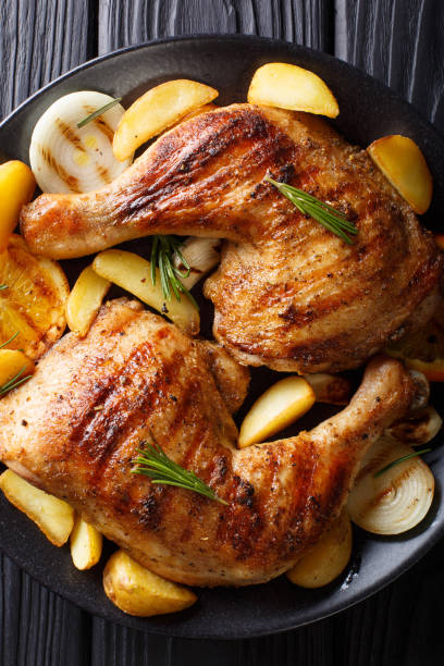 istock grilled chicken leg with oranges, onions and potatoes macro. Vertical top view 1053772654