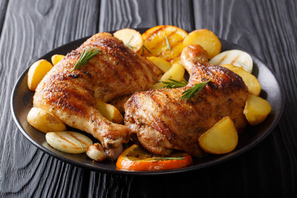 istock Hot fried chicken legs with grilled oranges, lemon, onion, garlic and potatoes close-up. horizontal 1053772676