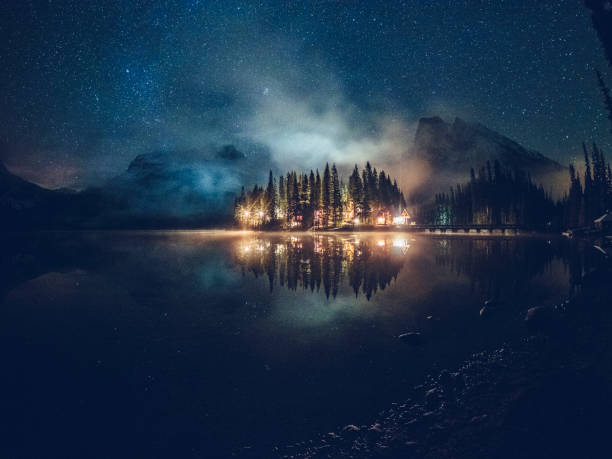 smaragdgrünen see mit beleuchtete hütte unter der milchstraße - lake night winter sky stock-fotos und bilder