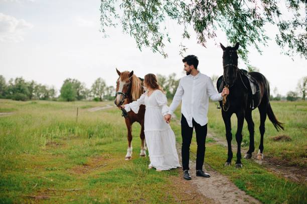 istock Couple Standing By Horses On Field 1053791574