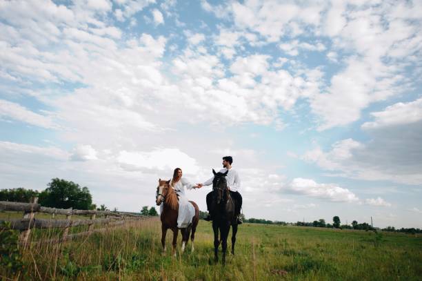 istock Couple Riding Horse On Field 1053791580