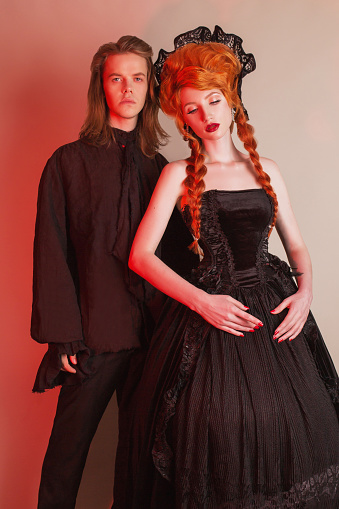 Gotische Paar Halloween Kostuum Bleke Undead Vampier In Edwardian Kleding Gothic Kostuum Voor Halloweenfeest Roodharige Vrouw In Zwarte Carnaval Jurk Vampier Koppel Op Donkere Stockfoto en meer beelden van
