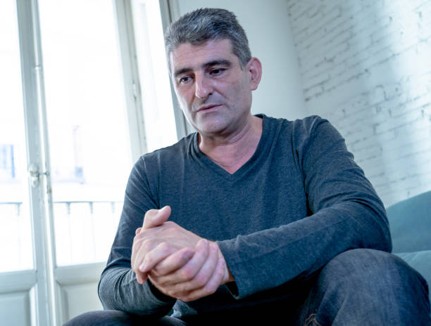 istock Attractive man feeling desperate sad looking worried depressed thoughtful and lonely suffering depression on couch at home in middle age crisis mental health personal problems and life style concept. 1053795944