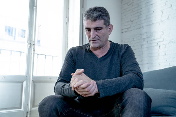 istock Attractive man feeling desperate sad looking worried depressed thoughtful and lonely suffering depression on couch at home in middle age crisis mental health personal problems and life style concept. 1053795970