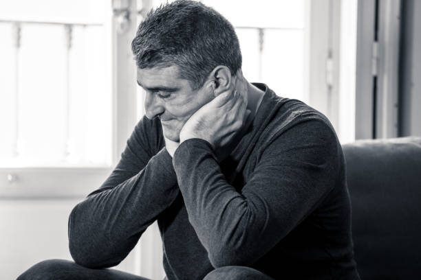 istock Attractive man feeling desperate sad looking worried depressed thoughtful and lonely suffering depression on couch at home in middle age crisis mental health personal problems and life style concept. 1053796006