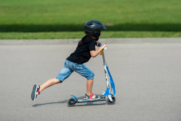 istock Side View Of Boy Riding Push Scooter On Road 1053801084