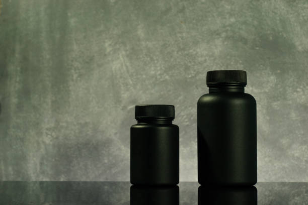 istock Black Bottle for pills on a black glass table. Beautiful background. 1053804116