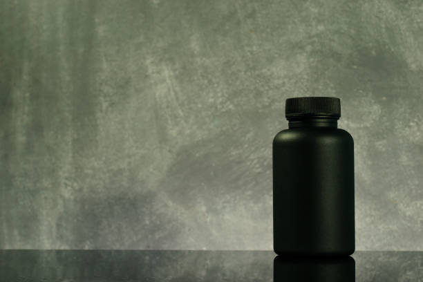 istock Black Bottle for pills on a black glass table. Beautiful background. 1053805802