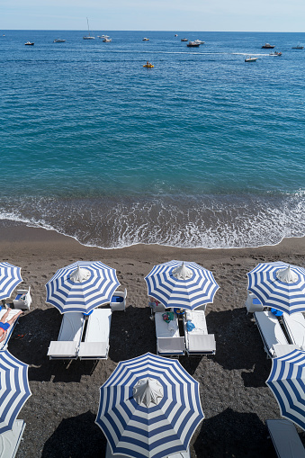 Italy. Amalfi Coast. Blue and white beach umbrellas on the beach of Positano.
