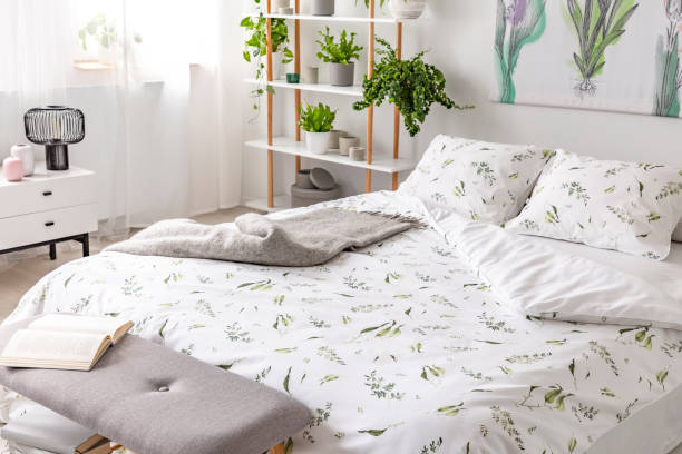 istock Green plant pattern on white bedding and pillows on a bed in a nature loving bedroom interior. Real photo. 1053812570
