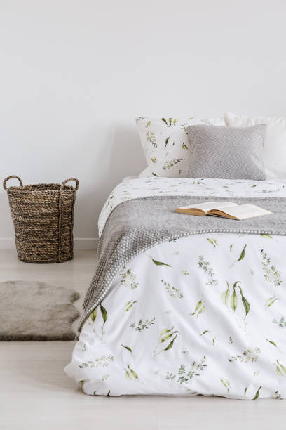 istock Raw scandinavian style bedroom interior with a bed dressed in natural fabric sheets, pillows and blanket. Empty white background wall. Real photo. 1053812578