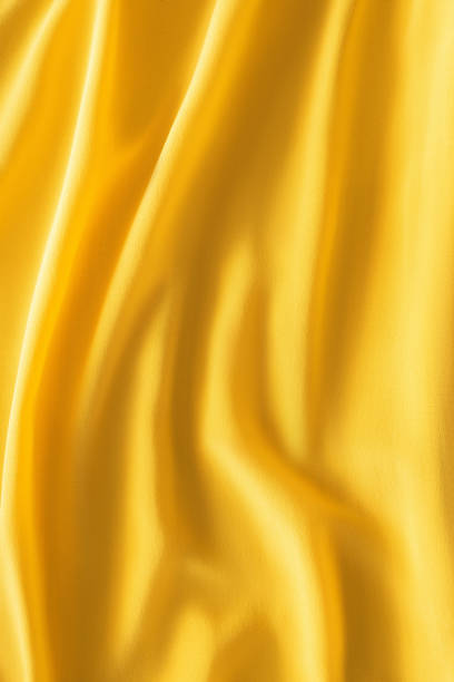 istock full frame of wavy yellow silk cloth as background 1053816834