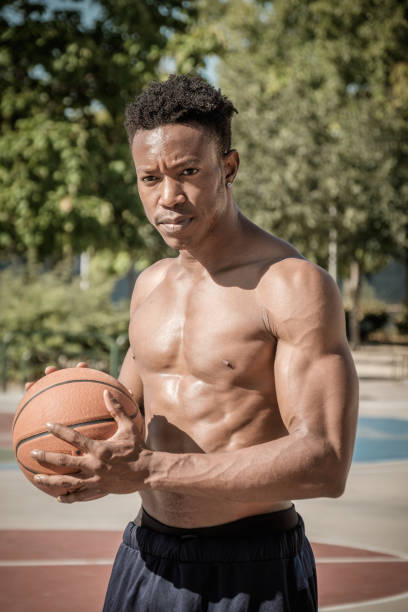 Afroamerican young man playing street basketball in the park stock photo
