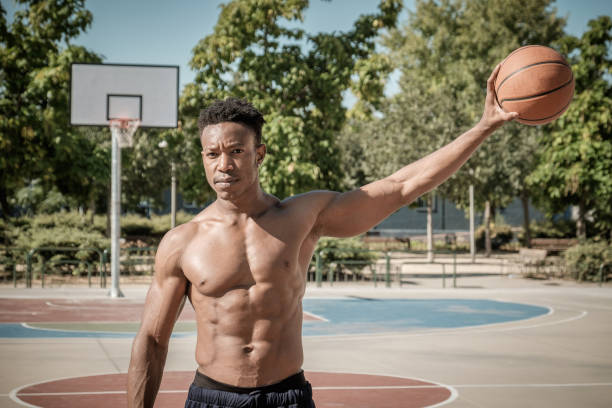 Afroamerican young man playing street basketball in the park stock photo