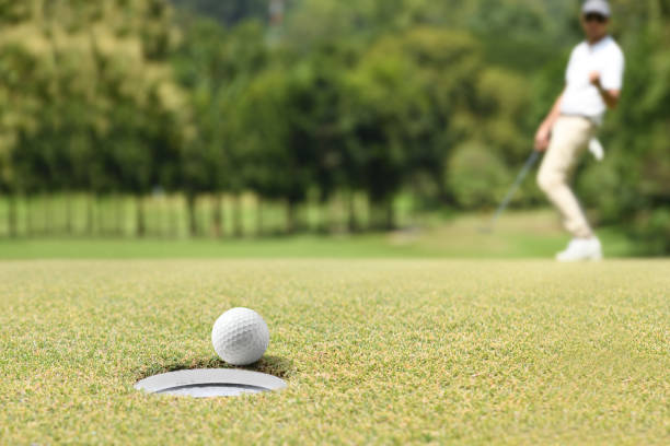 istock Man golfer cheering after a golf ball on a golf green 1053820932