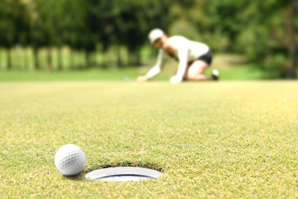 istock Woman golfer cheering after a golf ball on a golf green 1053821066