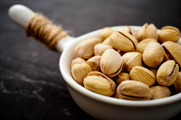 white bowl full of delicious pistachios on an old black table