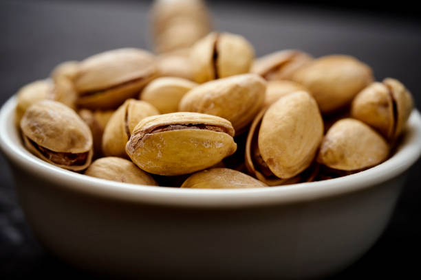 white bowl full of delicious pistachios on an old black table