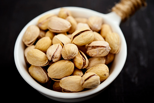 white bowl full of delicious pistachios on an old black table