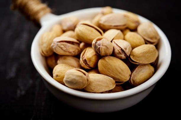 white bowl full of delicious pistachios on an old black table