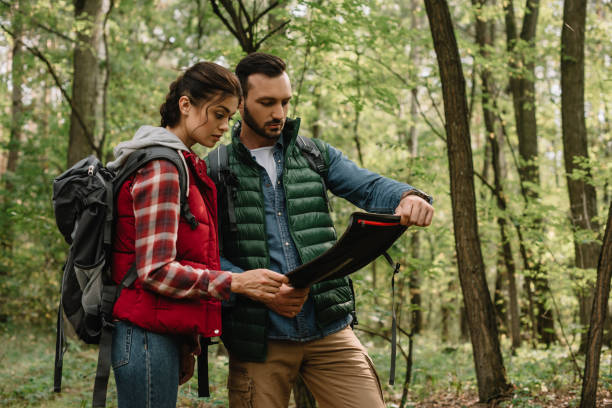 istock man and woman looking for destination on map while hiking in forest together 1053828410