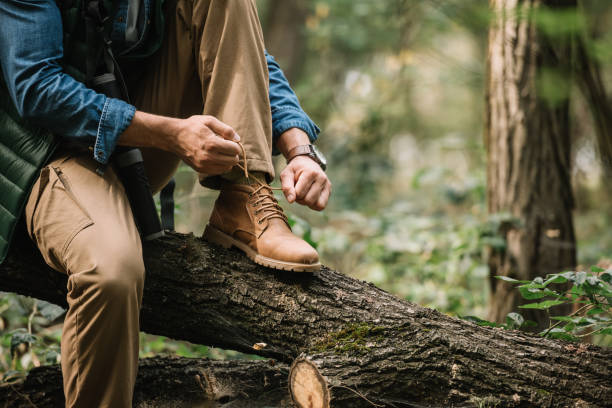 istock partial view of man tying shoelaces on log while hiking in forest alone 1053828464
