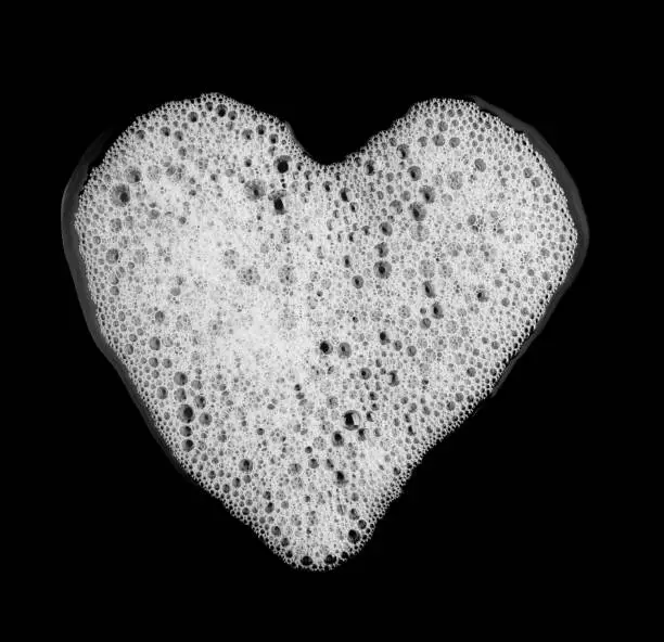 Photo of Bubble foam of soap shampoo heart shape isolated on black background top view object health concept