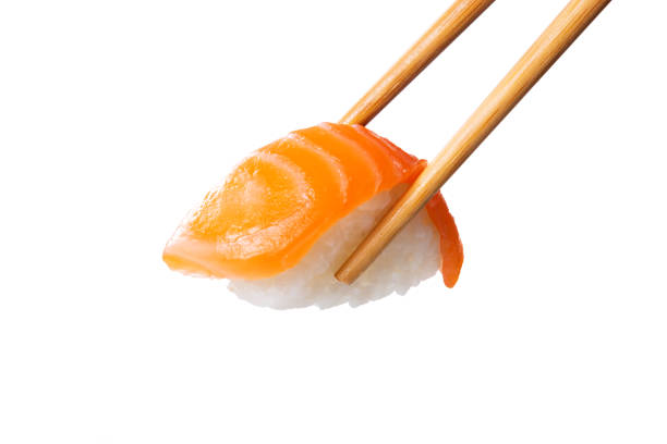 Closeup of salmon nigiri held with bamboo chopsticks. Fresh sushi nigiri isolated on white background. Eating sushi at restaurant. Japanese cuisine with rice and raw fish.