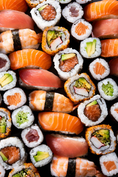 Japanese sushi collection Top view of variety of sushi food. High angle view of nigiri, maki, hosomaki, uramaki and roll with tuna, salmon, avocado and shrimp in a row. Traditional japanese food with raw fish and rice. sushi stock pictures, royalty-free photos & images