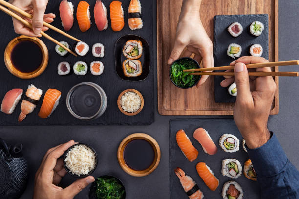 partage et manger des sushis - eating men food chopsticks photos et images de collection