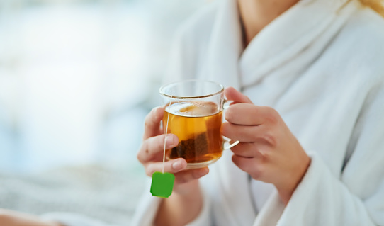 Cropped shot of an unrecognizable young woman relaxing at home with a glass of tea