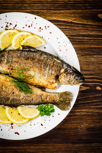istock Fried fish on white plate on wooden background 1053873718