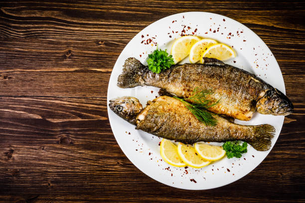 istock Fried fish on white plate on wooden background 1053873872