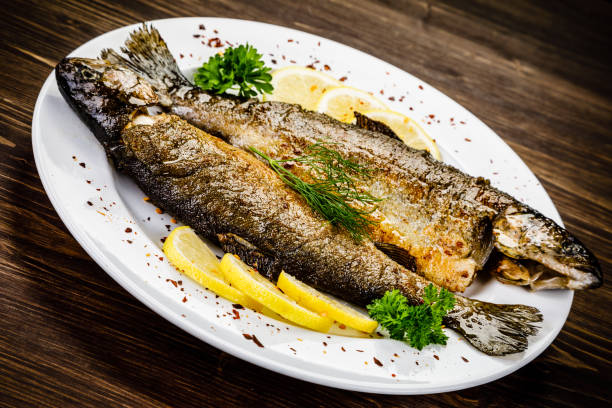 istock Fried fish on white plate on wooden background 1053874064
