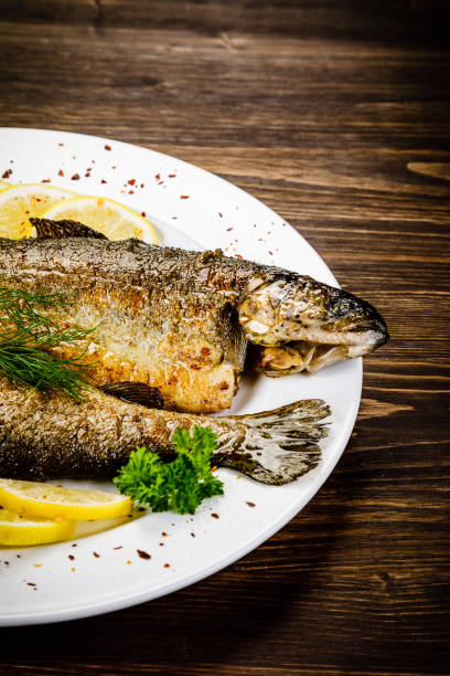 istock Fried fish on white plate on wooden background 1053875168