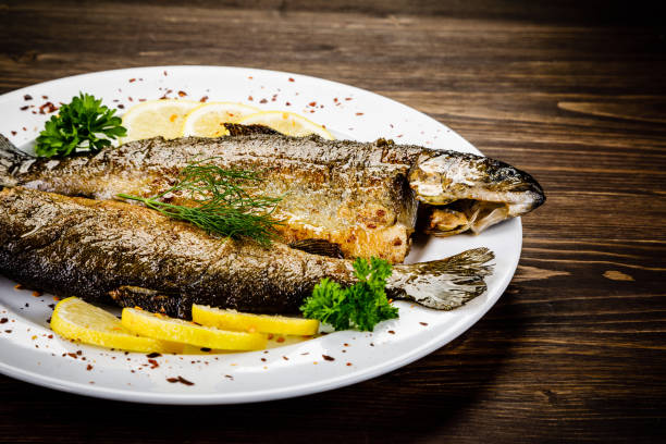 istock Fried fish on white plate on wooden background 1053875340