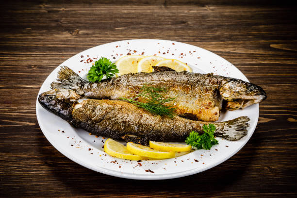 istock Fried fish on white plate on wooden background 1053875506