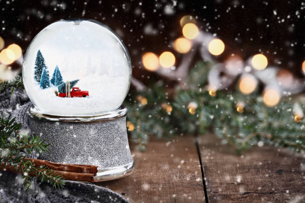 Snow Globe with Old Pick Up Truck Rustic image of a snow globe with old pick up tuck hauling a Christmas tree surrounded by pine branches, cinnamon sticks and a warm gray scarf with gently falling snow flakes. snow globe photos stock pictures, royalty-free photos & images
