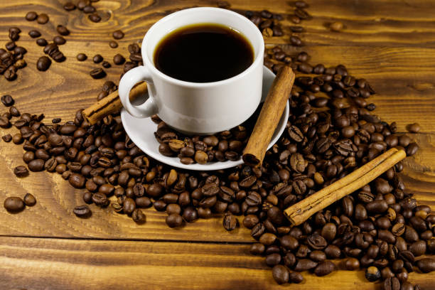 istock Cup of coffee, roasted coffee beans and cinnamon sticks on wooden table 1053875778
