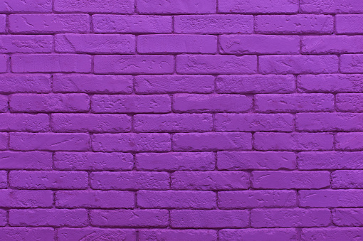 ultraviolet brick wall painted at saturated purple colour. closeup texture background