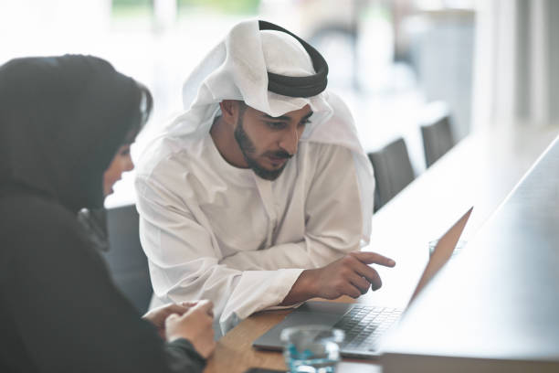 emiratischer unternehmer diskutieren über laptop - zurückhaltende kleidung stock-fotos und bilder