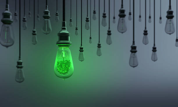 Ecologic Light Bulb Standing Out From the Crowd A Light Bulb includes tree between the others on dark background. Can be used ecology, energy, leadership, innovation and individuality concepts.  (3d render) surge stock pictures, royalty-free photos & images