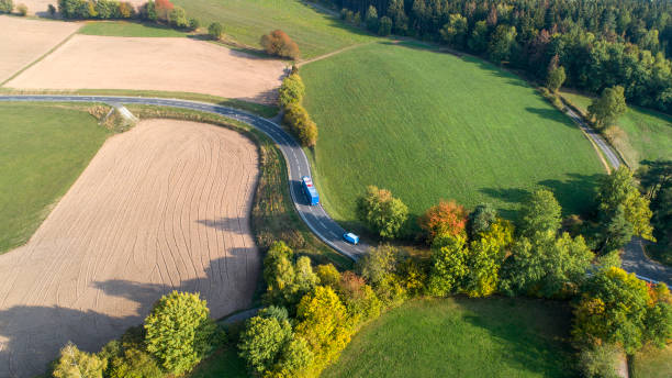 istock Road through autumnal rural scene - aerial view 1053897480