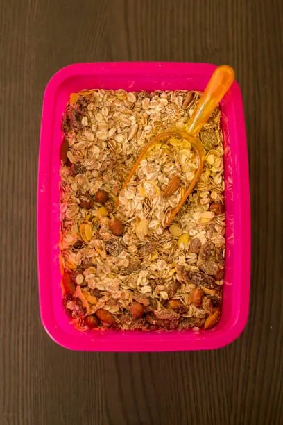 Pink container with oatmeal and nuts, close-up