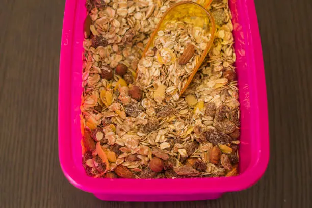Pink container with oatmeal and nuts, close-up